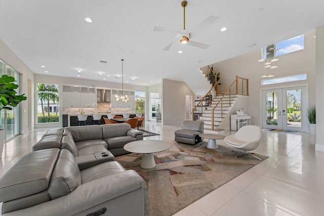 tiled living room with ceiling fan with notable chandelier, french doors, and a wealth of natural light