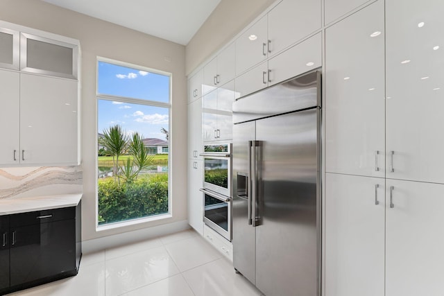 kitchen featuring appliances with stainless steel finishes, light tile patterned floors, and white cabinets