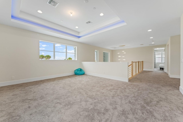 spare room featuring light carpet and a tray ceiling