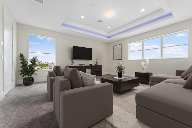 carpeted living room with a tray ceiling