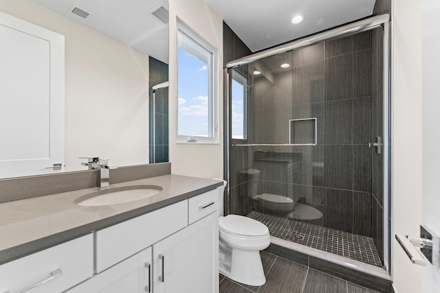 bathroom with tile patterned flooring, vanity, toilet, and walk in shower