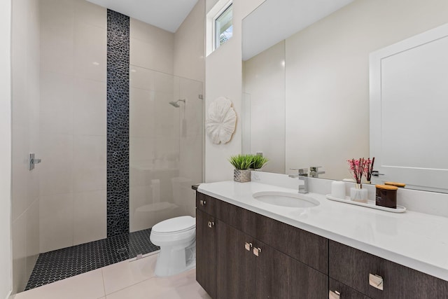 bathroom with toilet, a tile shower, and vanity