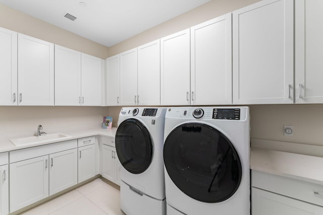 laundry area featuring light tile patterned floors, sink, cabinets, and washing machine and dryer