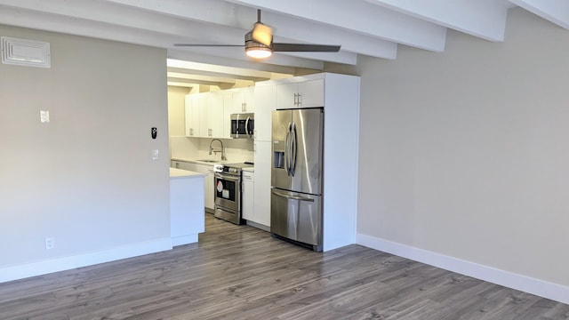 kitchen with white cabinetry, beam ceiling, hardwood / wood-style flooring, ceiling fan, and stainless steel appliances