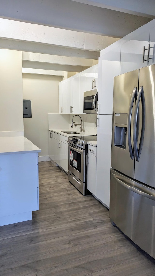 kitchen with hardwood / wood-style floors, appliances with stainless steel finishes, sink, and white cabinets