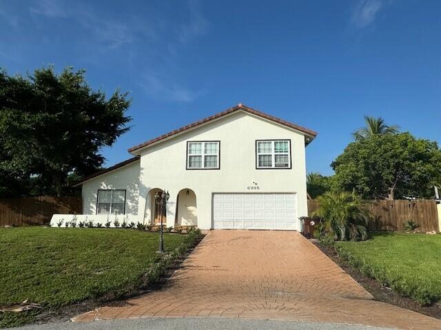 6785 Escondida Dr, Lake Clarke Shores, FL 33406 - view of front of property featuring fence, an attached garage, stucco siding, a front lawn, and decorative driveway