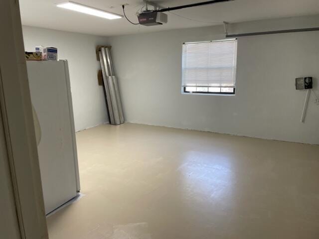 garage featuring white fridge and a garage door opener