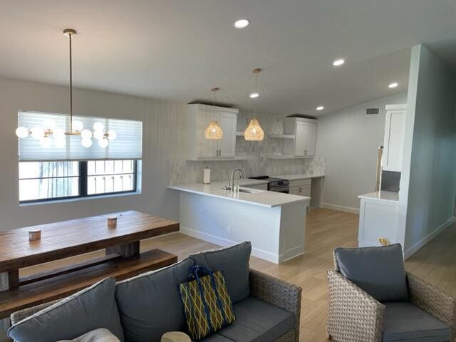 kitchen with decorative light fixtures, kitchen peninsula, and white cabinetry