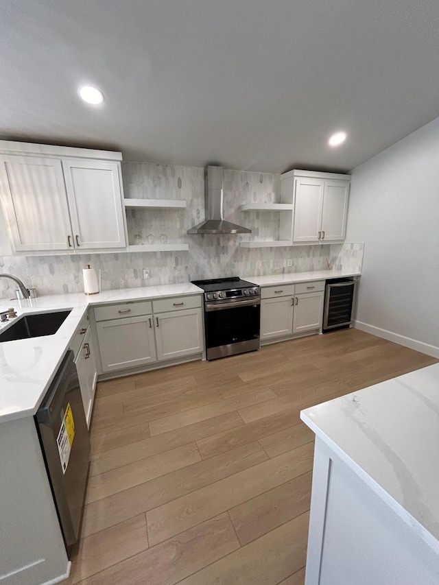 kitchen featuring beverage cooler, dishwasher, wall chimney range hood, white cabinetry, and electric range