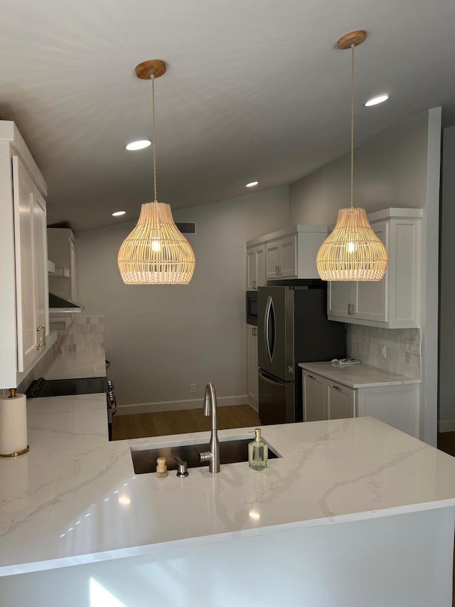 kitchen featuring white cabinetry, kitchen peninsula, stainless steel fridge, hanging light fixtures, and sink