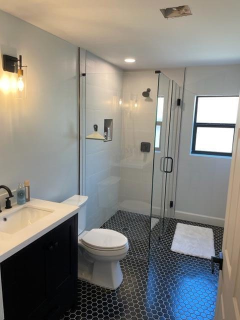 bathroom with toilet, vanity, and a shower with door