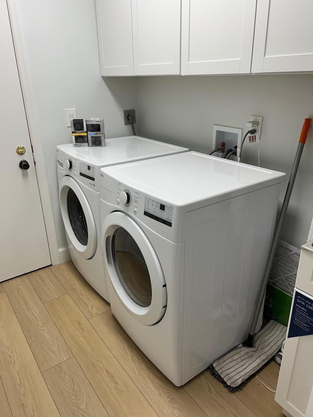 washroom featuring light wood-type flooring, cabinets, and washing machine and clothes dryer