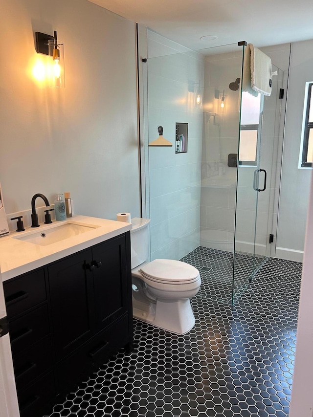 bathroom featuring toilet, vanity, and a shower with shower door