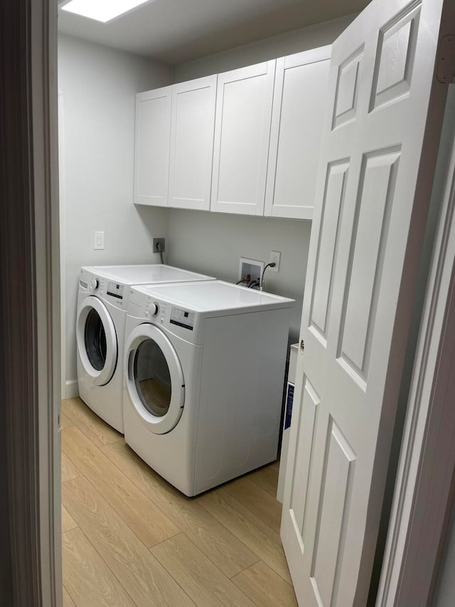 laundry area with cabinets, light hardwood / wood-style flooring, and washing machine and clothes dryer