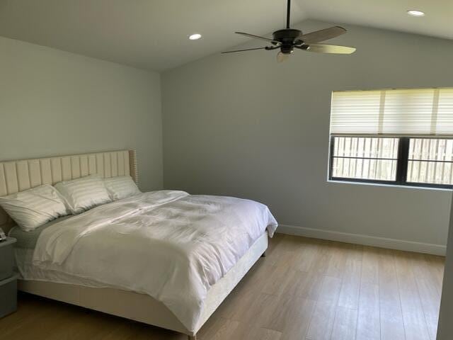 bedroom with ceiling fan, vaulted ceiling, and light hardwood / wood-style flooring