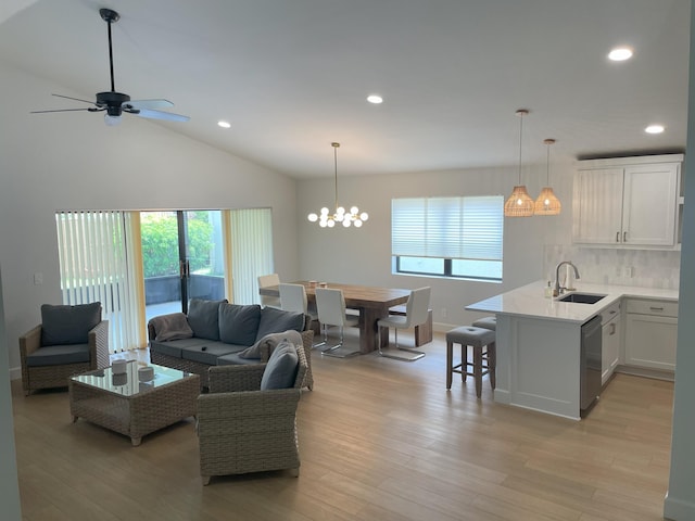 living room featuring ceiling fan with notable chandelier, sink, light hardwood / wood-style flooring, and lofted ceiling