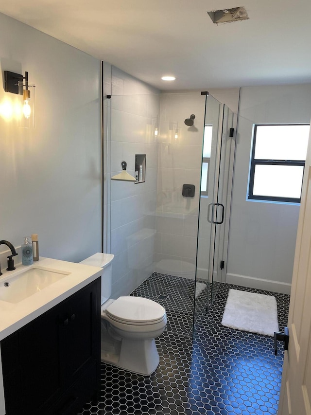 bathroom featuring toilet, vanity, and a shower with shower door