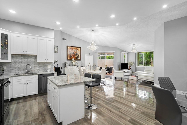 kitchen with white cabinets, wood-type flooring, dishwashing machine, and lofted ceiling