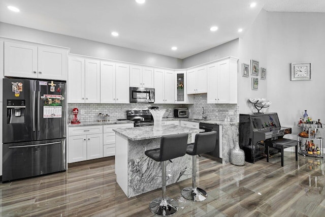 kitchen with light stone counters, white cabinetry, black appliances, and tasteful backsplash