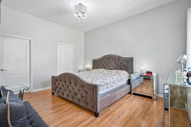 bedroom with a textured ceiling, a closet, a notable chandelier, and hardwood / wood-style floors