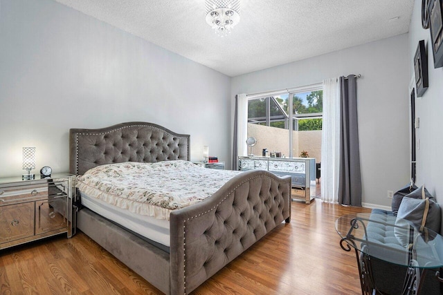 bedroom featuring a textured ceiling, an inviting chandelier, and light hardwood / wood-style floors