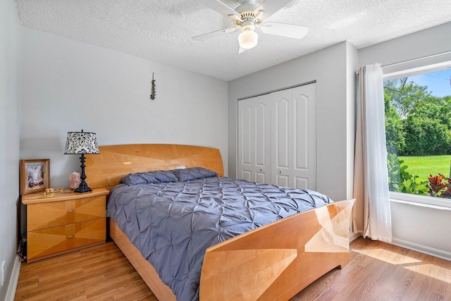 bedroom with a textured ceiling, a closet, ceiling fan, and light wood-type flooring