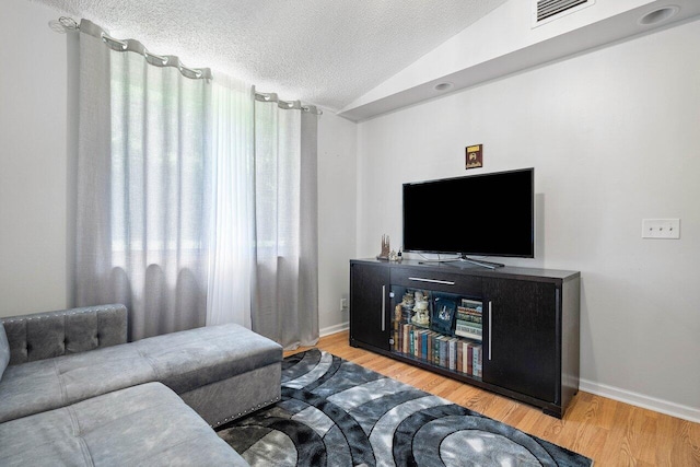 living room featuring light hardwood / wood-style floors, vaulted ceiling, and a textured ceiling