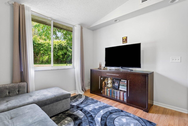 living room with a textured ceiling, plenty of natural light, vaulted ceiling, and light hardwood / wood-style flooring