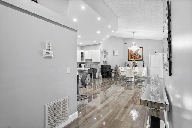 interior space featuring hardwood / wood-style floors, an inviting chandelier, a high ceiling, and a textured ceiling