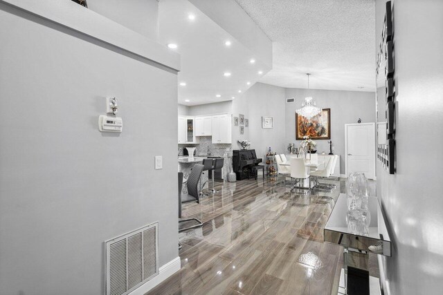 9859 Boca Gardens Cir Unit B, Boca Raton, FL 33496 - hall featuring a textured ceiling, visible vents, light wood-style floors, recessed lighting, and a notable chandelier