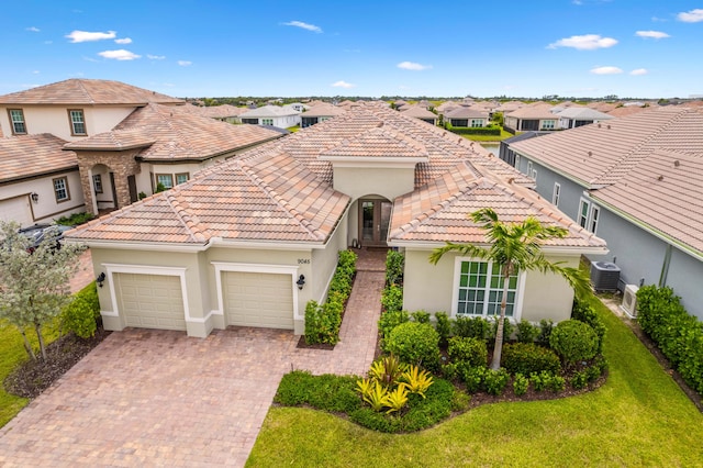 mediterranean / spanish-style home featuring a front lawn, central AC unit, and a garage