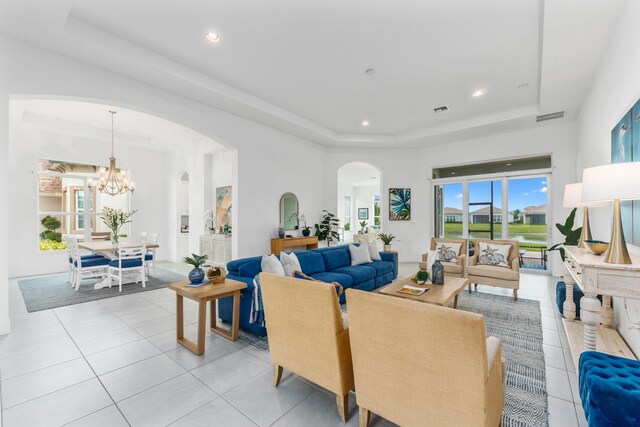 living room featuring light tile patterned floors, a notable chandelier, and a tray ceiling