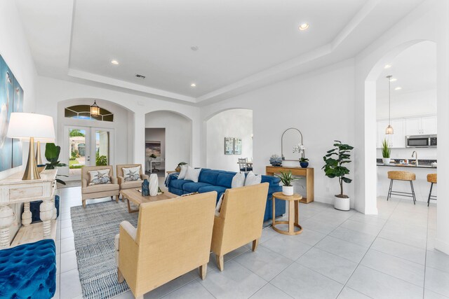 tiled living room featuring sink, a raised ceiling, and french doors