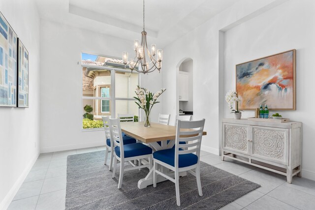 dining area featuring a raised ceiling, light tile patterned floors, and a chandelier