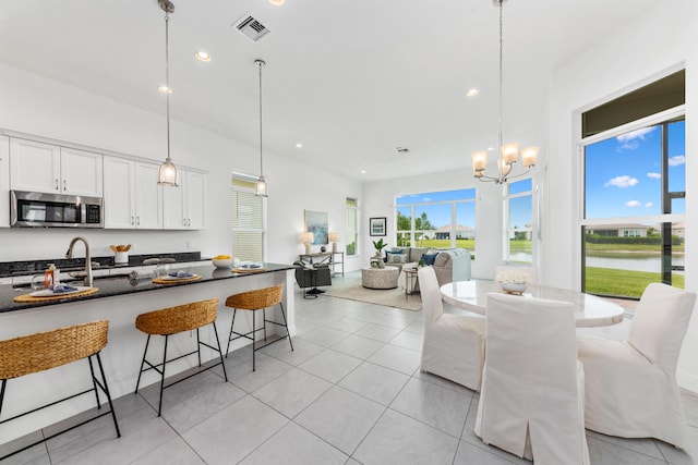 kitchen with pendant lighting, white cabinets, light tile patterned floors, and a kitchen bar