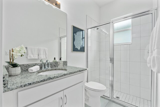 bathroom featuring tile patterned flooring, toilet, vanity, and walk in shower