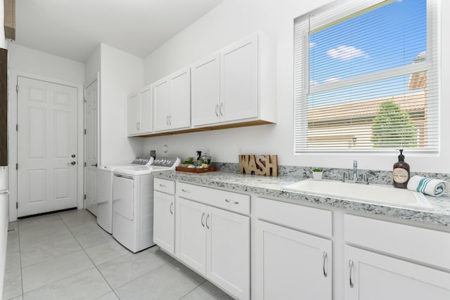 clothes washing area with light tile patterned floors, sink, washer and clothes dryer, and cabinets