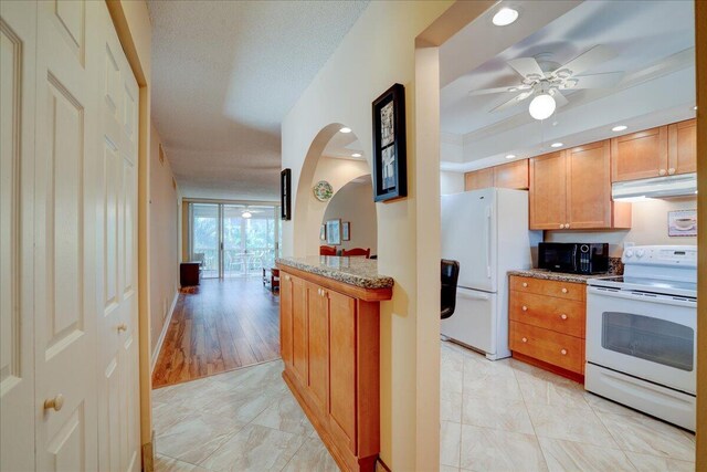 kitchen with ceiling fan, a raised ceiling, ornamental molding, light hardwood / wood-style floors, and white appliances