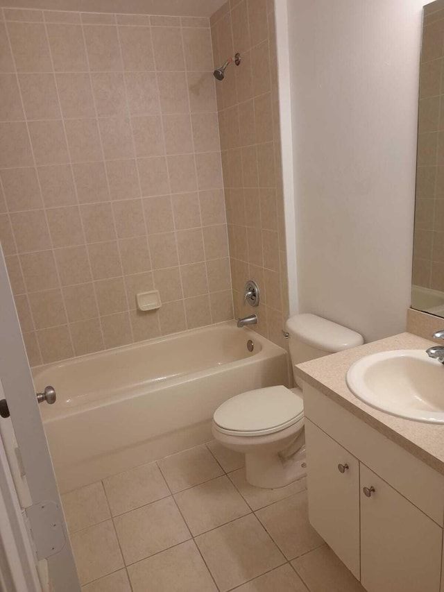 full bathroom featuring tile patterned flooring, tiled shower / bath, vanity, and toilet