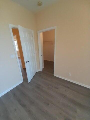 unfurnished bedroom with a spacious closet, a closet, and hardwood / wood-style flooring