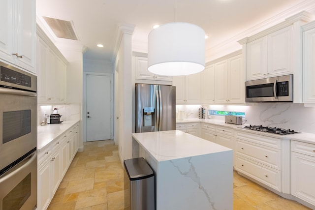 kitchen with appliances with stainless steel finishes, backsplash, white cabinetry, pendant lighting, and a center island