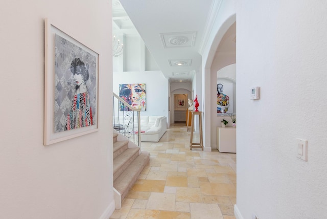 hall featuring arched walkways, stairway, baseboards, and stone tile floors