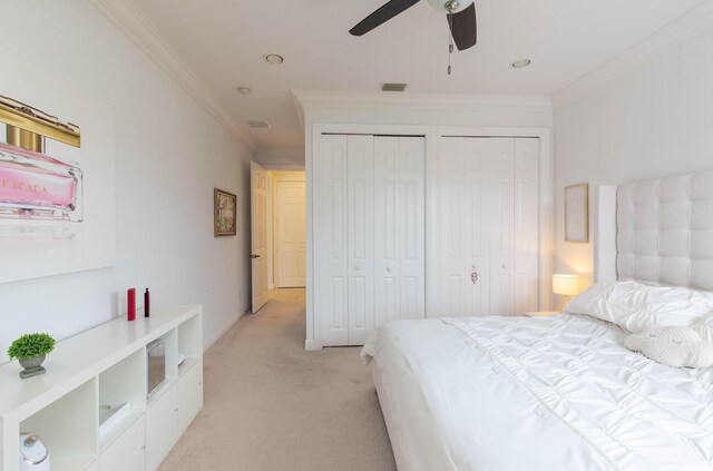 carpeted bedroom featuring ceiling fan, ornamental molding, and multiple closets