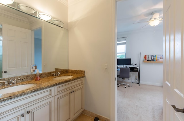 bathroom featuring baseboards, double vanity, a sink, and crown molding