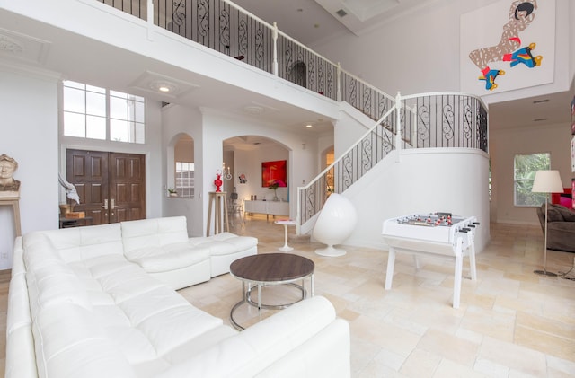 living room featuring light tile patterned floors, a towering ceiling, and ornamental molding