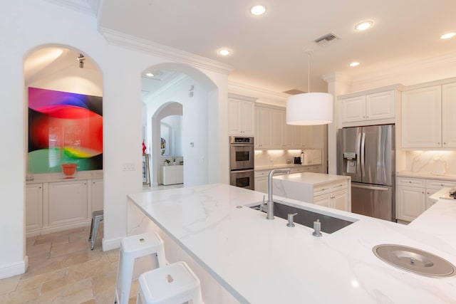 kitchen featuring arched walkways, visible vents, stainless steel appliances, crown molding, and a sink