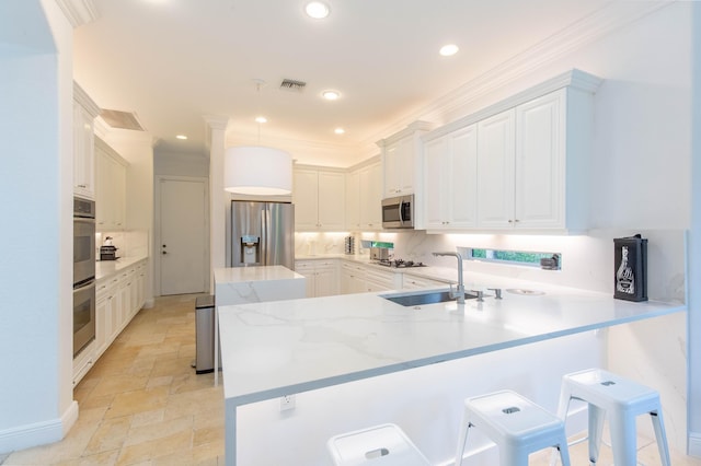 kitchen with stone tile floors, tasteful backsplash, appliances with stainless steel finishes, a sink, and a peninsula