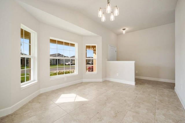 tiled empty room featuring a wealth of natural light, lofted ceiling, and an inviting chandelier