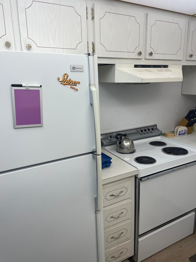 kitchen featuring hardwood / wood-style flooring, wall chimney exhaust hood, and white appliances