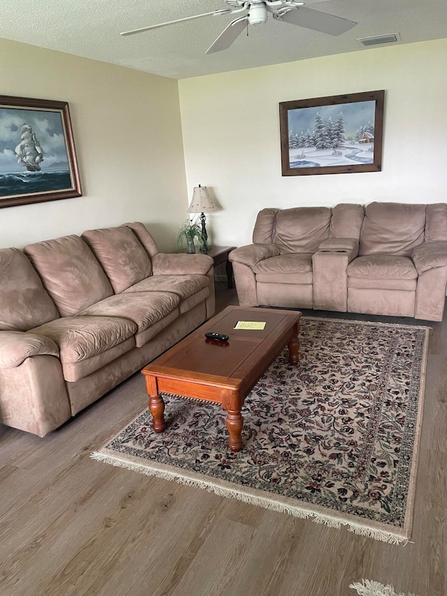 living room featuring a textured ceiling, ceiling fan, and wood-type flooring